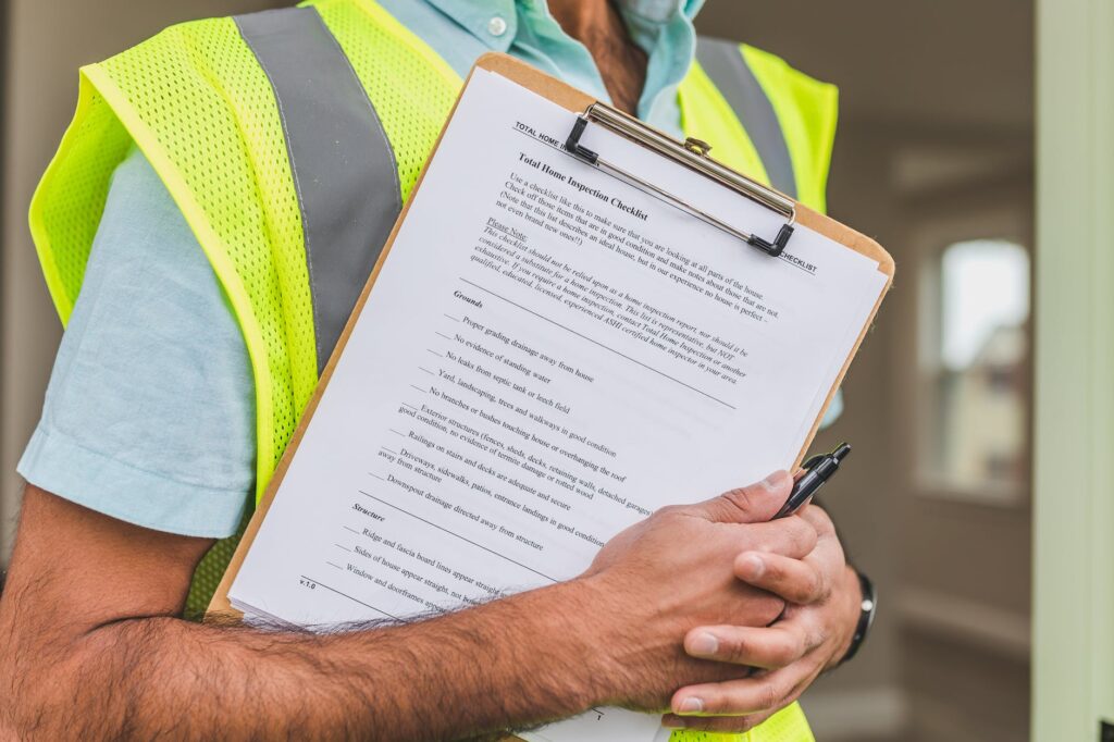 person in yellow reflective safety vest holding a pen and checklist of house inspection